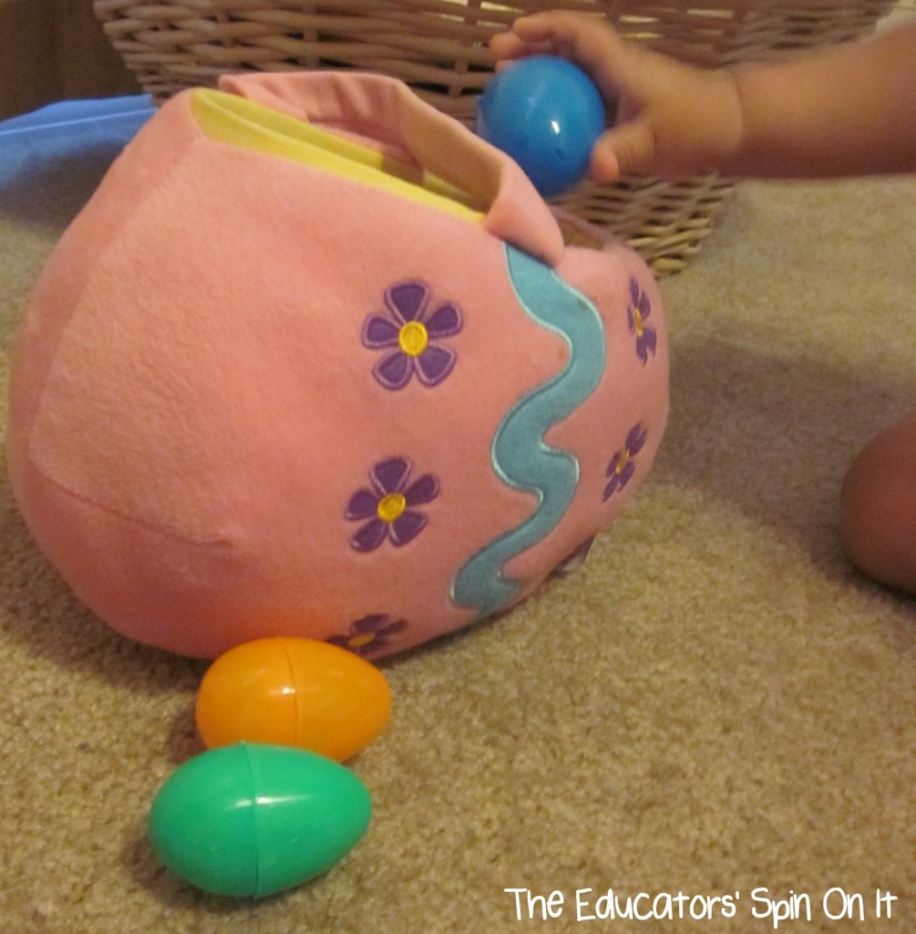 toddler placing easter eggs into soft egg shaped easter basket 