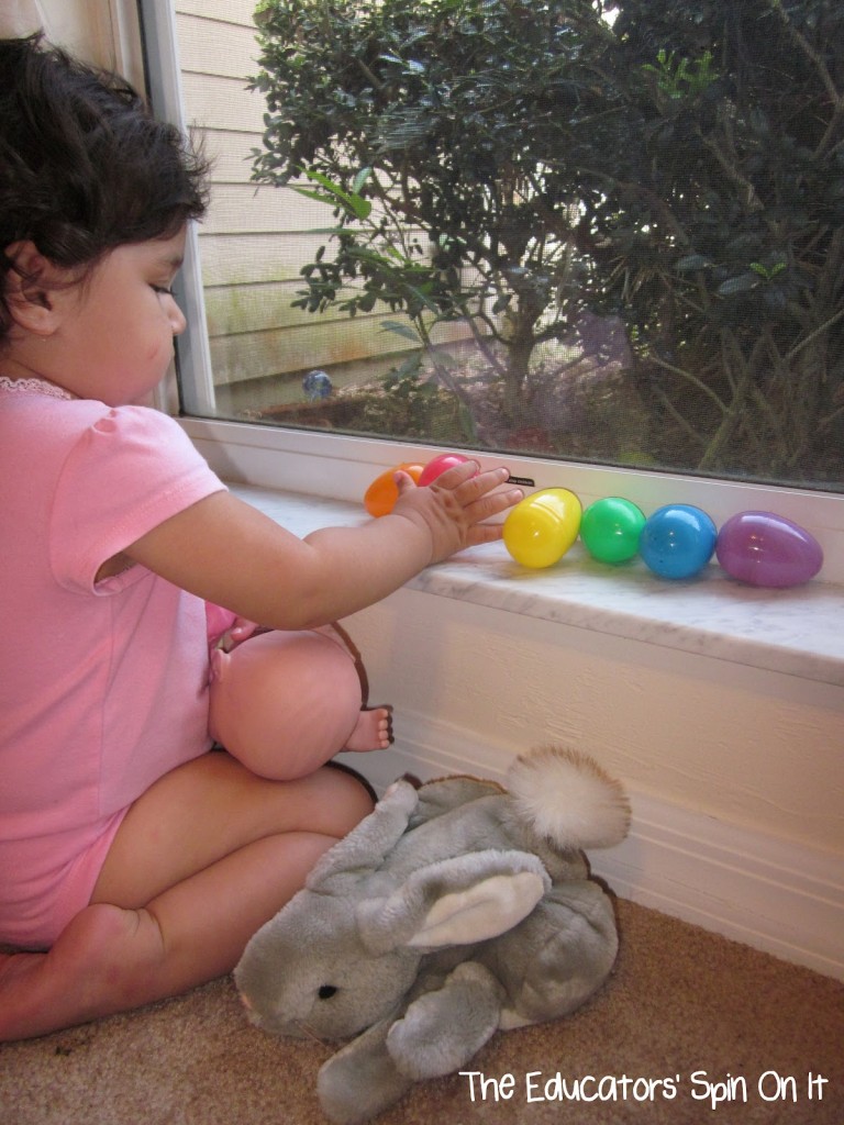 Toddler plying with Easter eggs putting in rainbow order 