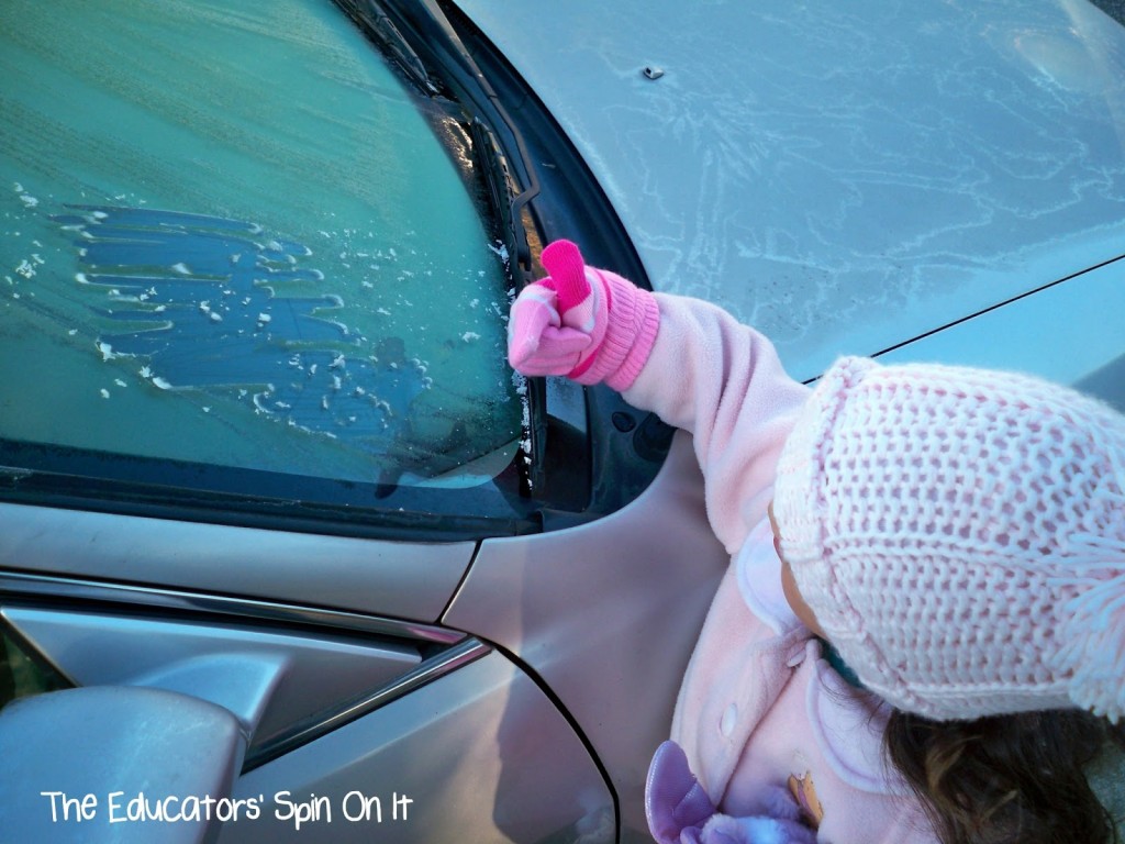 signs of winter frost on car with child scraping windshield 