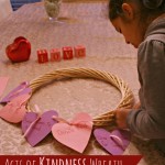 Random Acts of Kindness Wreath with child tying on heart onto wreath