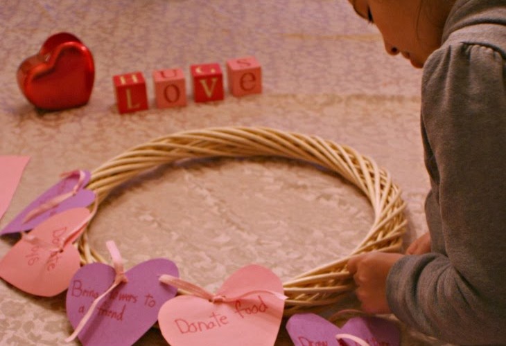 Random Acts of Kindness Wreath with child tying on heart onto wreath