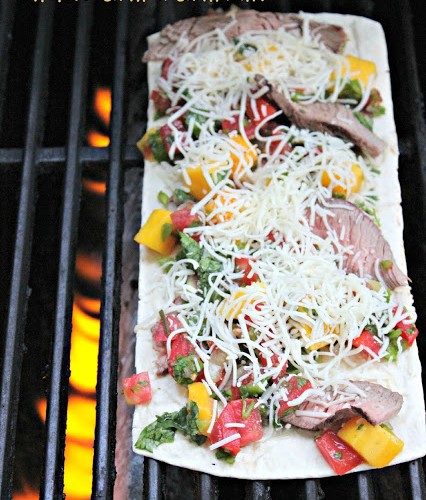 Flatbread pizza on grill with peppers, mangos, cheese and steak