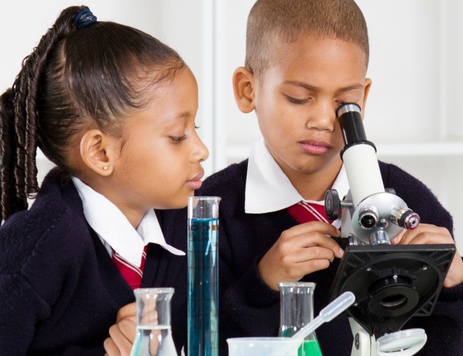 2 kids doing a science experiement in an elementary school classroom