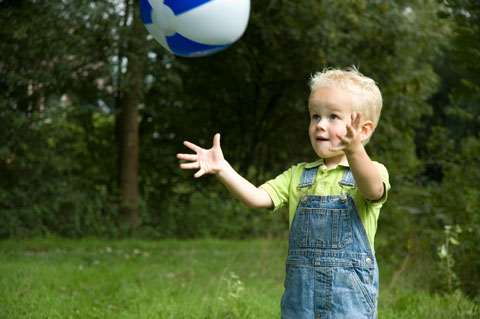 small boy playing with a ball outside