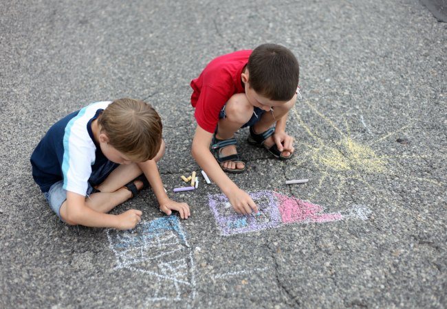 2 boys playing with sidewalk chalk