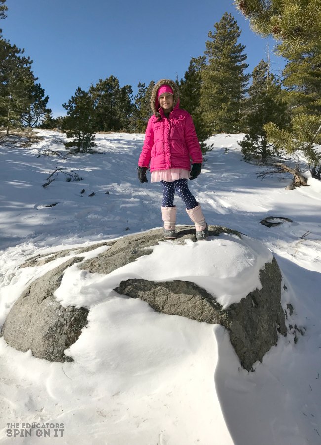 Hiking at Bear Lake in the Rocky Mountain National Park with snow covered boulder and young child. 