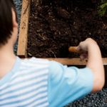Child digging in garden dirt to start a garden