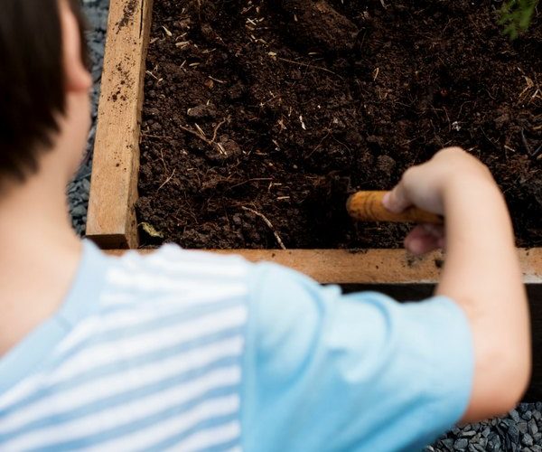 Child digging in garden dirt to start a garden