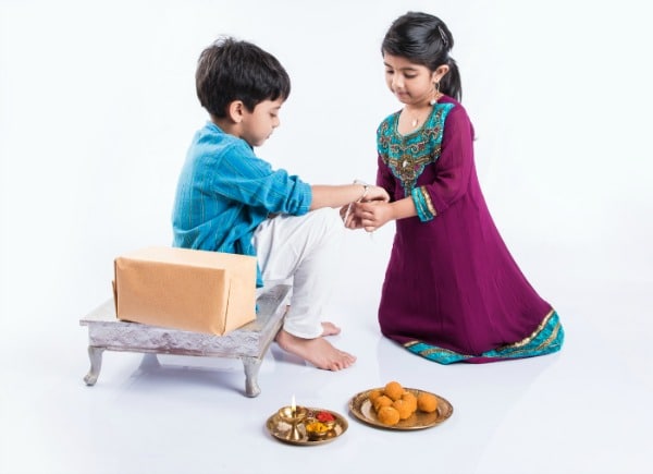 Sister trying rakhi bracelet onto brother for Rakshad Bandhan. 