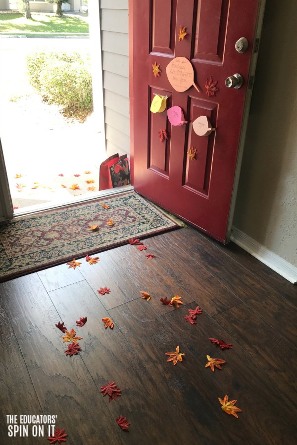 Front door entrance covered with fall leaves and sign about kindness