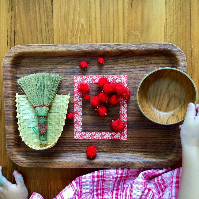 Young girl using small broom on wooden tray for Chinese New Year Activity