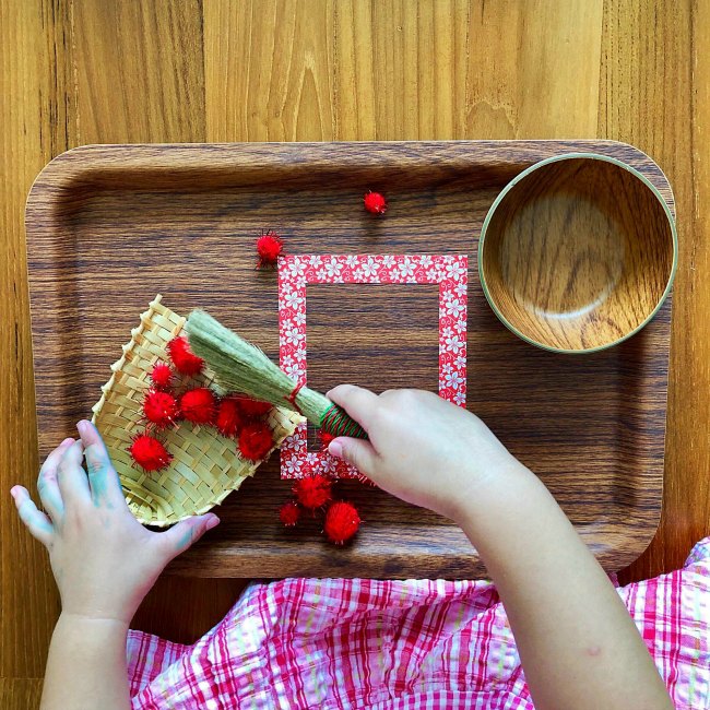 Young girl using small broom on wooden tray for Chinese New Year Activity