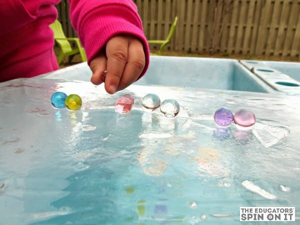 child playing with water beads on ice sheet