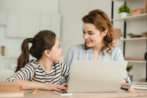 parent working from home with child sitting next to them at table