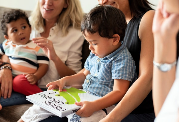 Child holding book during kids book club with moms group