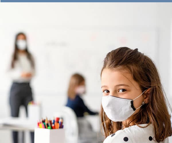 Child wearing mask in school setting to help to protect spread of COVID 19 in schools.