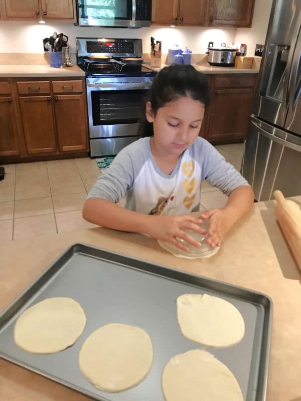 Child Cutting out circles for apple pie pockets recipe