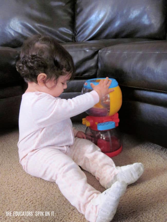 Baby playing with pretend toy gumball machine with toy balls